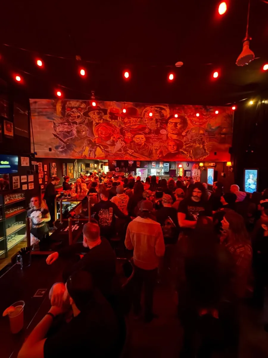Packed crowd at The Pale Horse with red lighting and horror mural